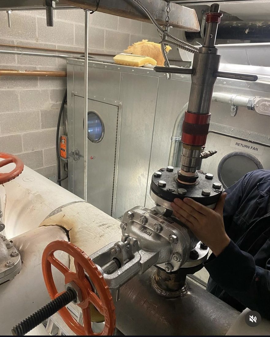 Hot tap fitting and flanged valve installed on a live insulated line with tapping equipment mounted above