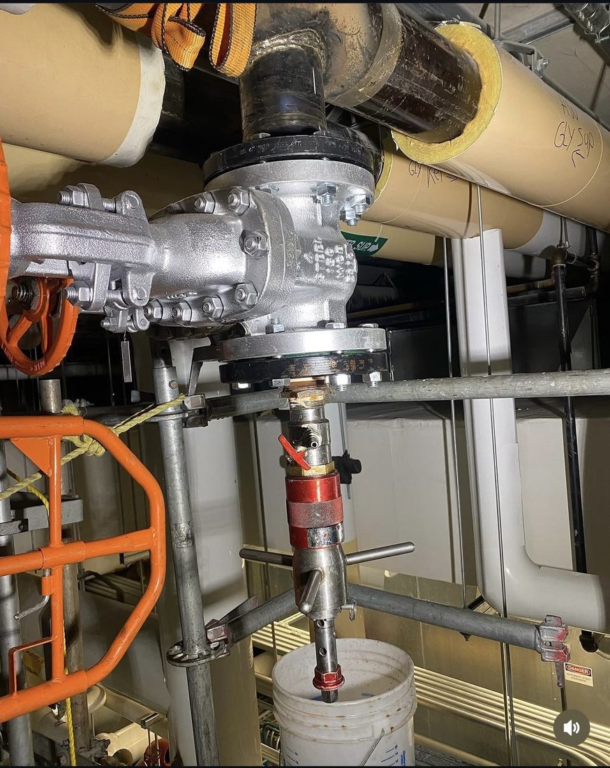 Large hot tapping machine mounted on an overhead process line in an industrial plant