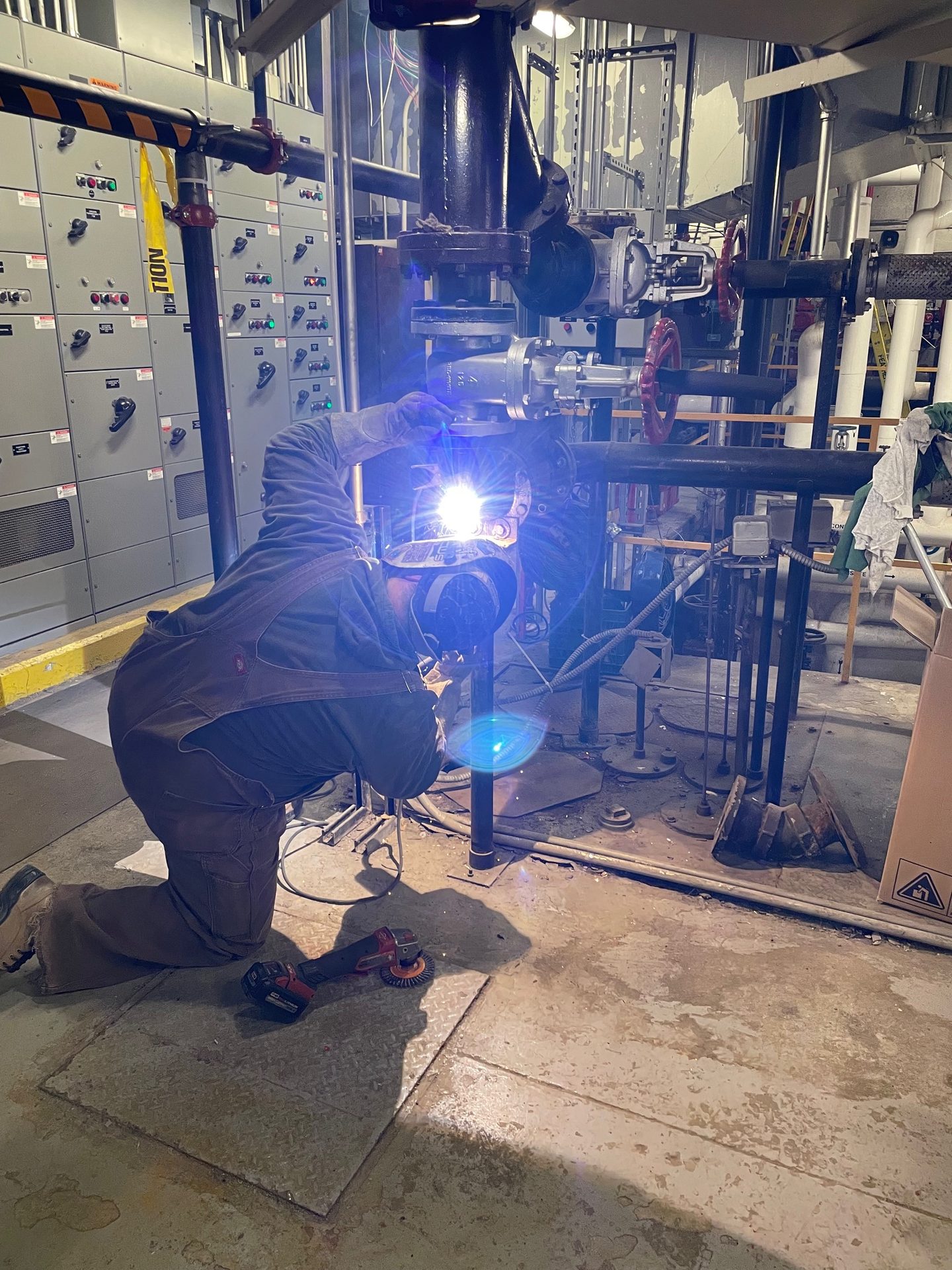 Welder working on pipe in a plant