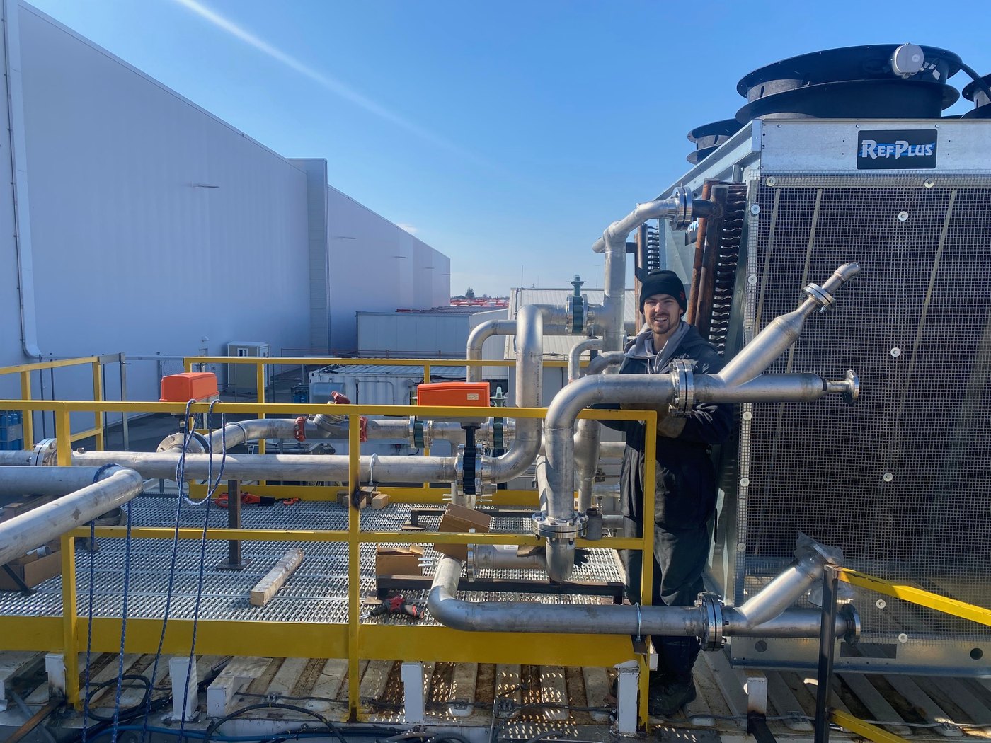 Stainless steel process piping installed on a rooftop chiller by an IMW technician